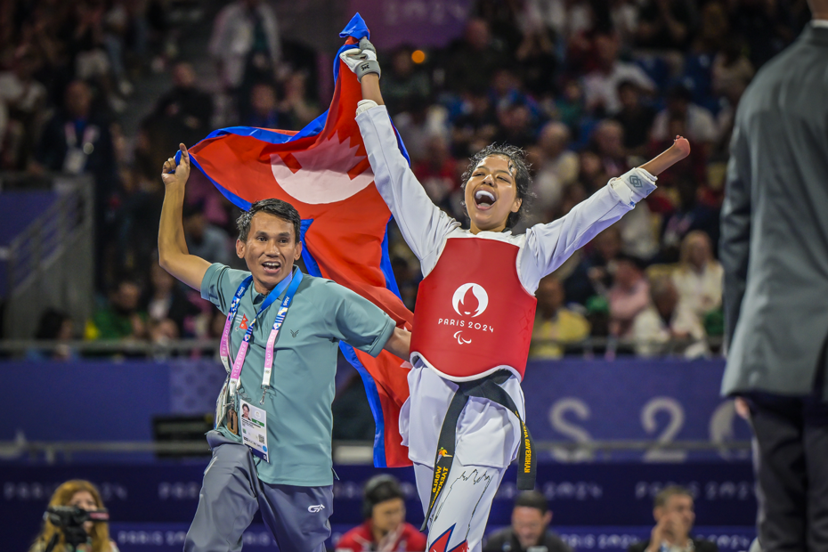 Palesha Goverdhan celebrates after winning a big medal for Nepal at the Paris 2024 Paralympics with coach Kabiraj Negi Lama hoisting the flag of Nepal at the Grand Palais in Paris.